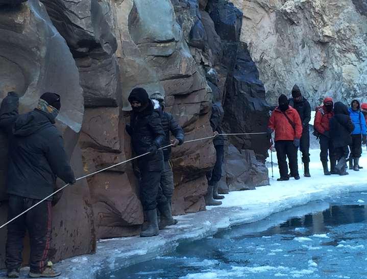 Using fixed rope for support to cross a tricky part on the Chadar Trek, Ladakh
